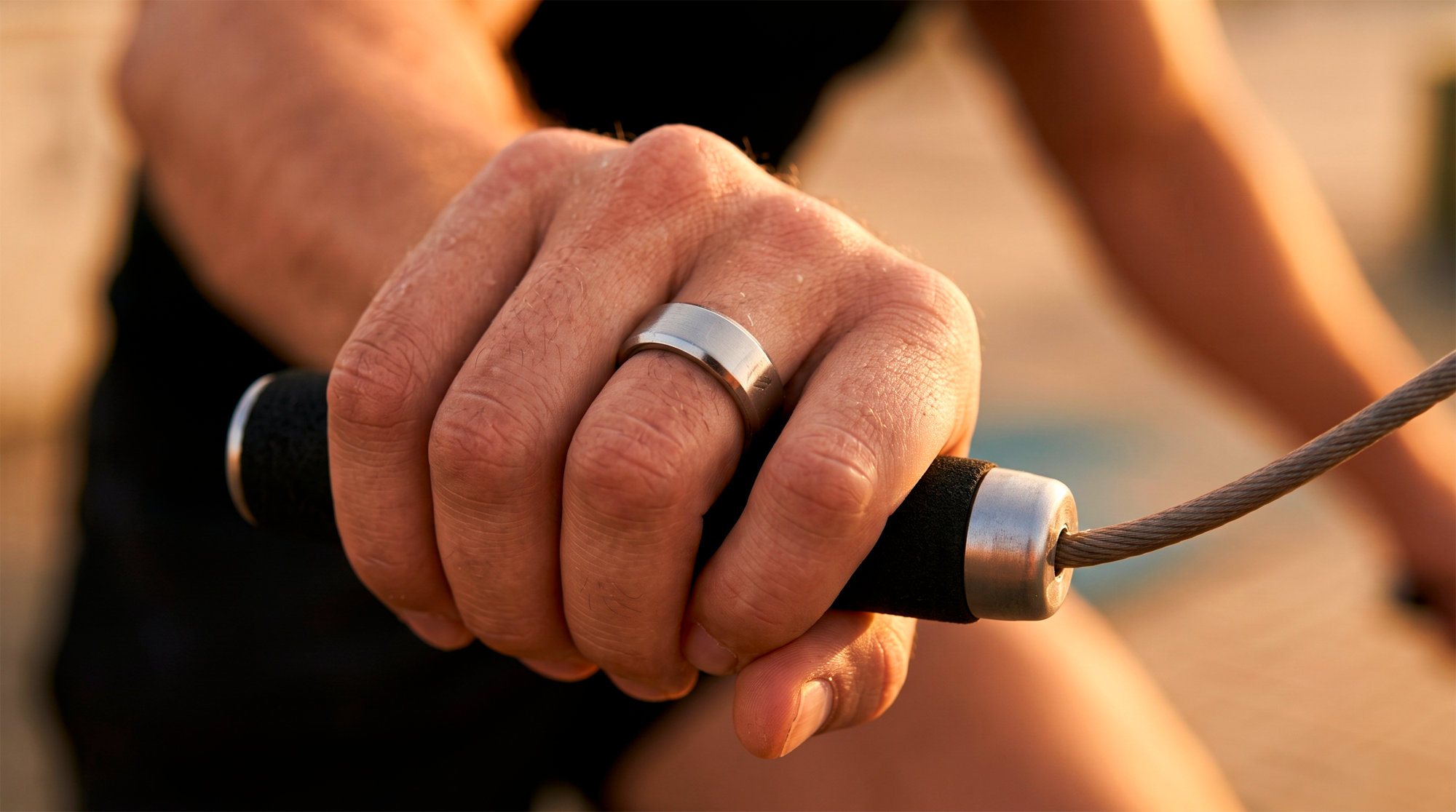 Mano con el anillo Sense agarrando una cuerda de entrenamiento, luz dura al aire libre
